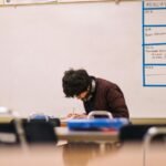 A high school student studying and solving problems in a classroom setting.